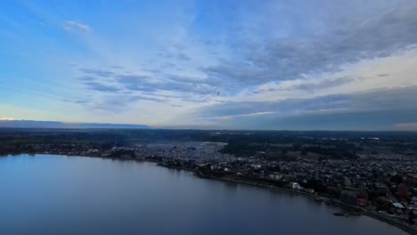 Aerial-view-of-the-city-of-Puerto-Varas,-Chile-with-a-small-plane-passing-through-its-air-territory