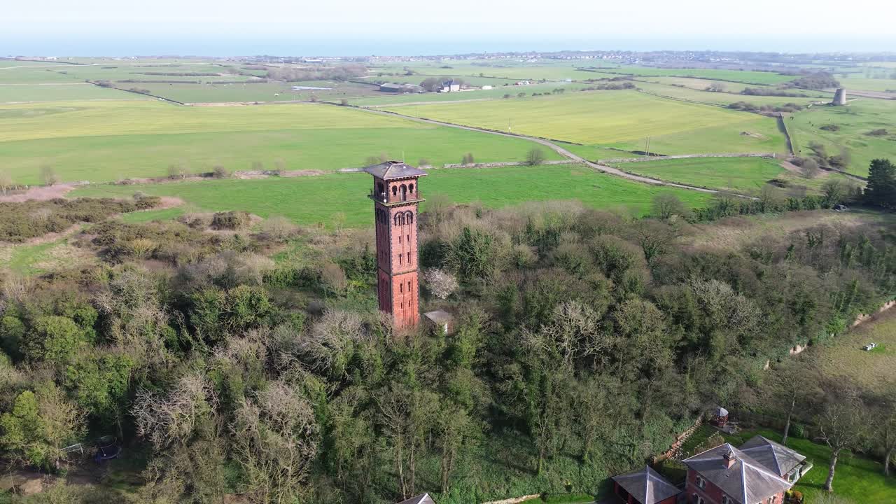 Orbita di drone della Torre dell'Acqua di Cleadon a Cleadon, South Tyneside, guardando a est attraverso terreni agricoli rurali, boschi e una costa e un mare distanti sotto cieli limpidi diurni