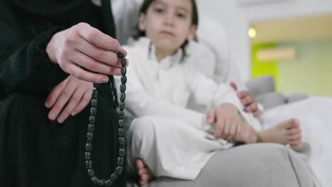 muslim woman praying at home with kid in background