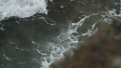 Epic-wave-burst-of-drops-on-foamy-water-with-pan-from-down-to-up