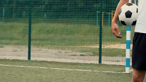 close up of an unrecognizable football player standing and holding soccer ball on a street football pitch 1