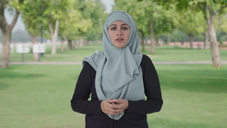 serious muslim woman talking to the camera in park