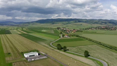 Slow-rising-aerial-boom-shot-above-hayfields-near-Sansimion-and-Sanmartin,-Romania