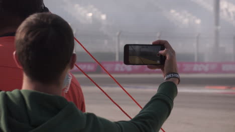 espectador tomando una foto o un video de una carrera de coches a la deriva