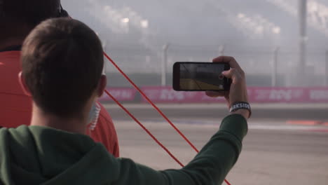 spectator taking photo/video of a drifting car race