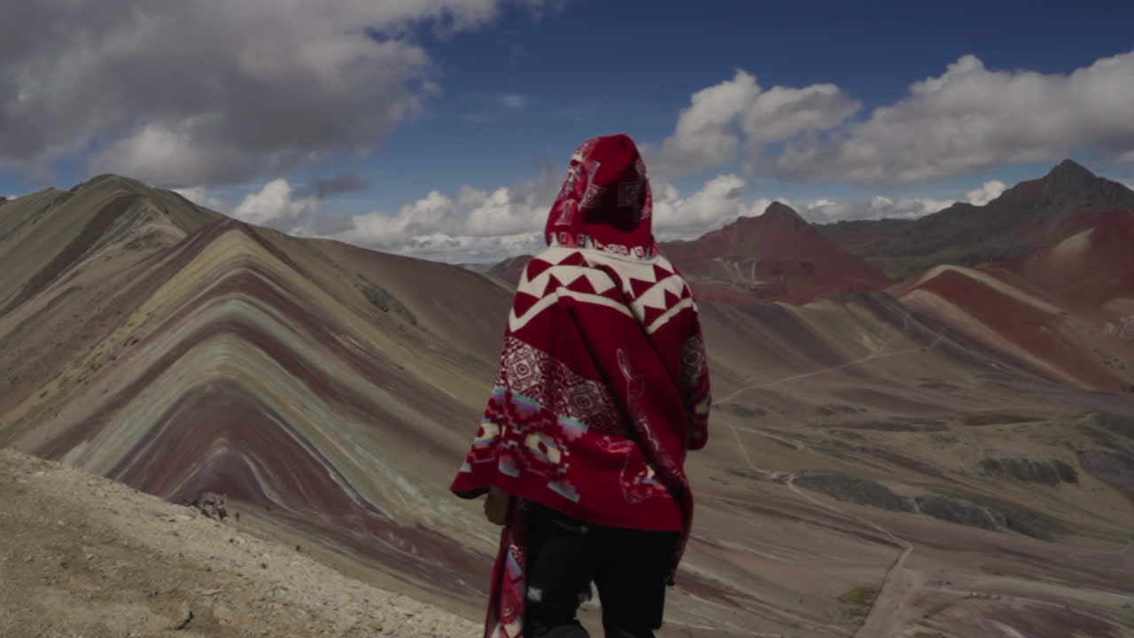 Turista con poncho peruviano rosso esplora la Montagna Arcobaleno in Perù. Sette colori, Cusco, Perù