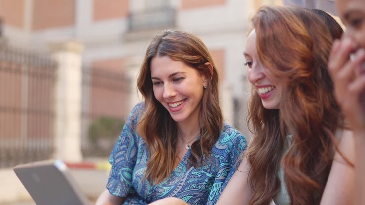 Happy Young Women Sharing a Tablet Outdoors