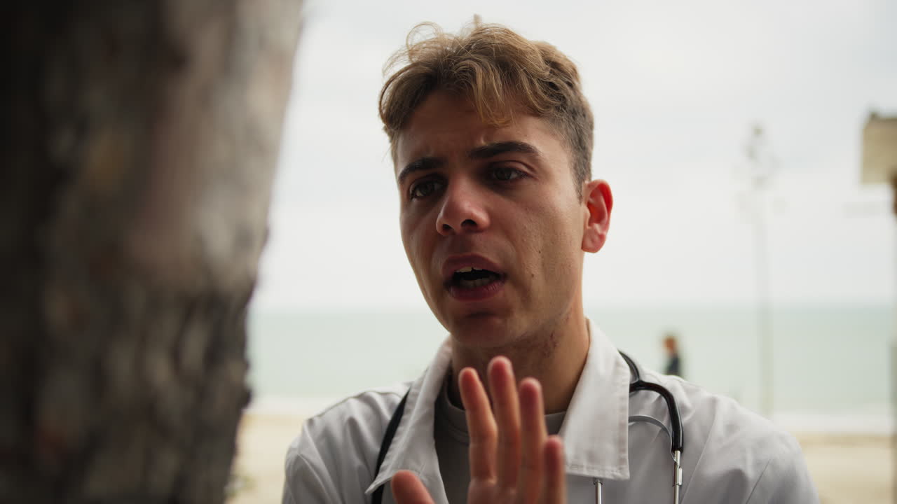 техник разговаривает с стволом дерева, как сумасшедший в парке.