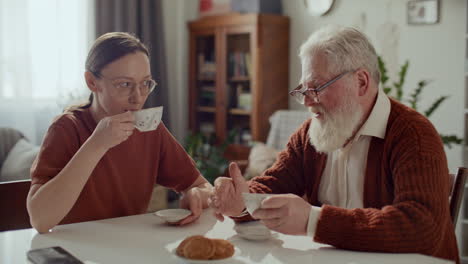 senior man talking to granddaughter during teatime at home