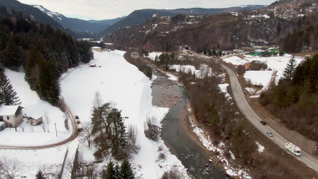 aérea de la zona italiana en los alpes con tráfico, nieve, lago y gente