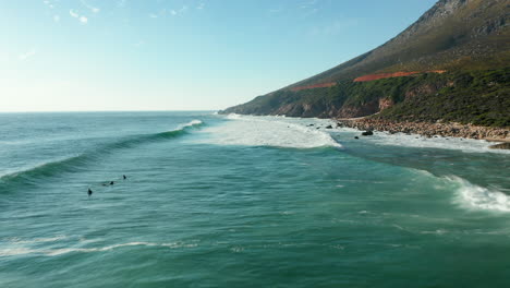 surfistas surfeando en la playa de la bahía de kogel con olas perfectas en ciudad del cabo, sudáfrica