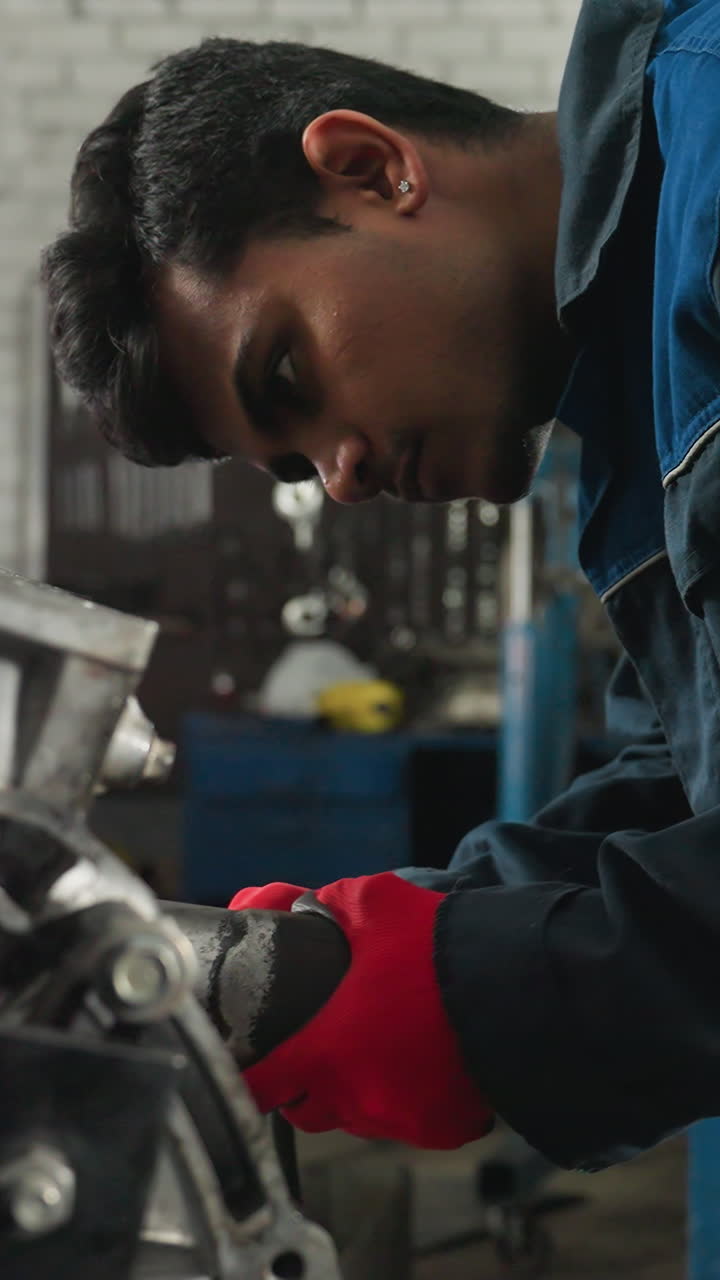 mecánico con guantes rojos utiliza herramienta neumática en el bloque del motor en el taller industrial, realizando reparaciones mecánicas precisas, trabajador enfocado en uniforme azul ajusta los componentes del motor