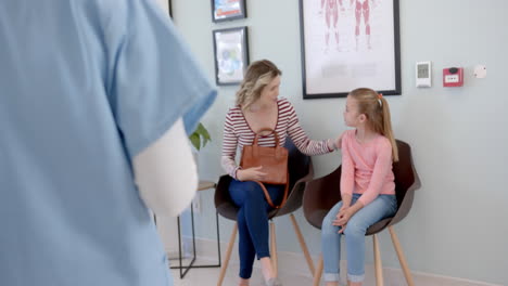 happy caucasian girl patient, mother and female nurse talking in hospital reception, slow motion