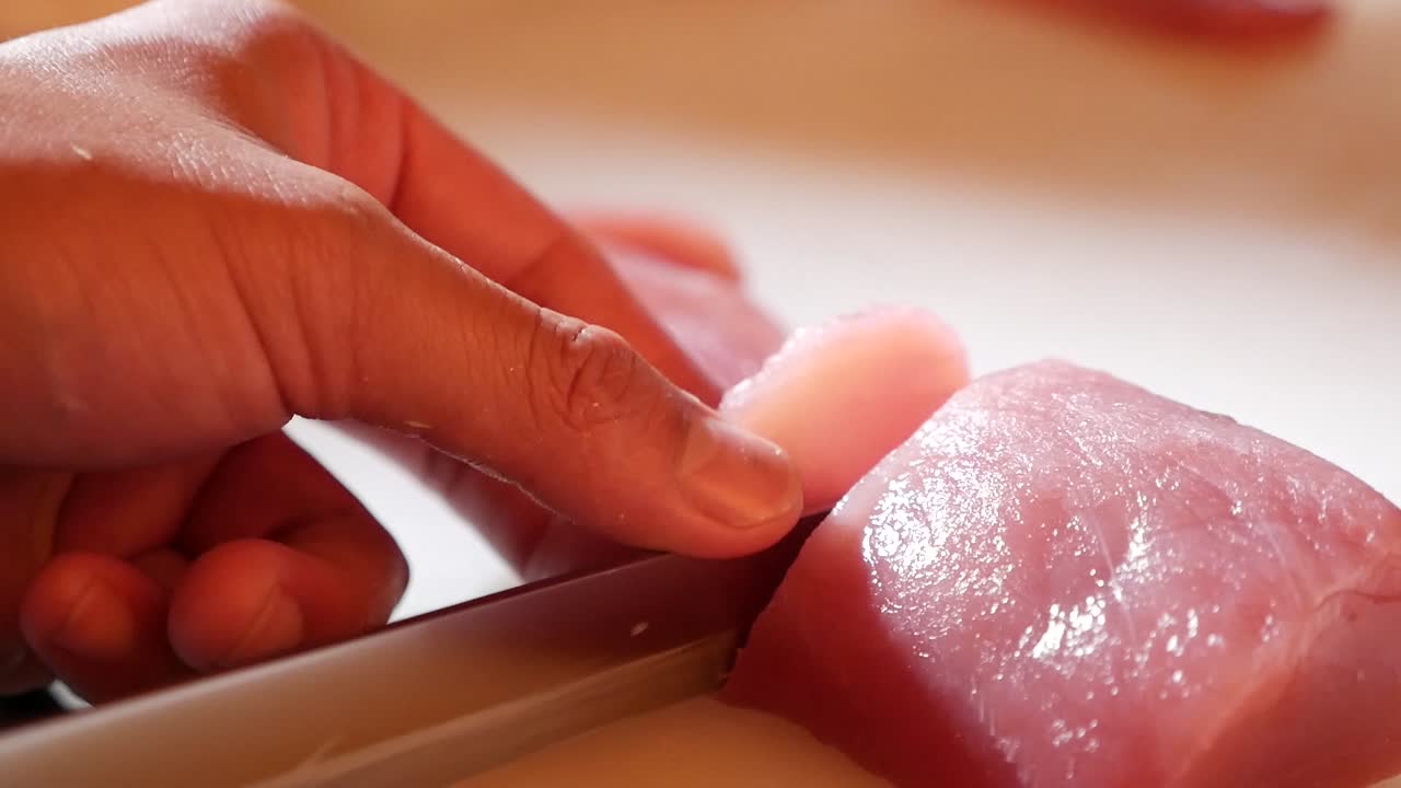 use un cuchillo a mano para cortar maguro rosa en sashimi de bocado pequeño, cerrar-2