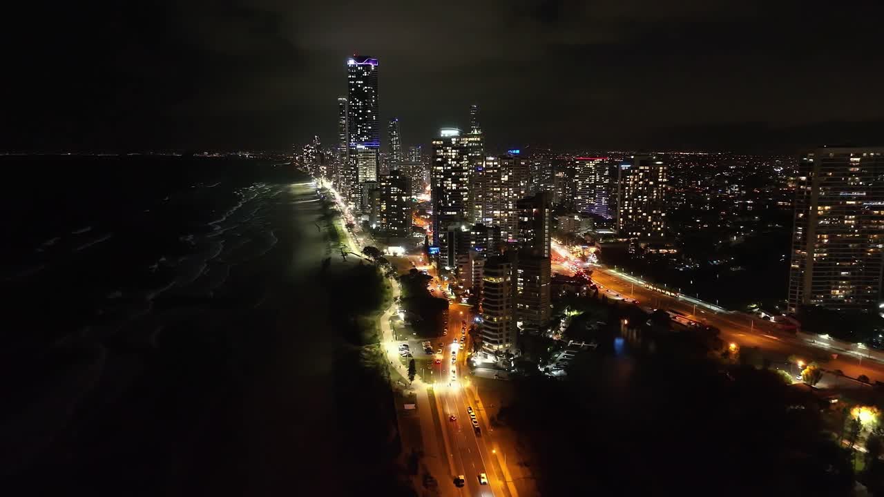 voando alto da praia principal para o paraíso dos surfistas, as luzes da noite brilhando sobre as ondas brilhantes quebrando nas praias da costa dourada