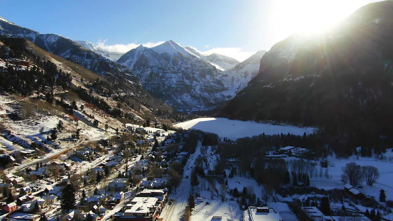 vista aérea cinematográfica de drones de la estación de esquí de montaña telluride en el centro de colorado de pintorescas montañas paisaje, lago y edificios históricos luz del sol temprano mediados del invierno movimiento hacia adelante