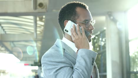 Smiling-businessman-with-cell-phone-at-train-station