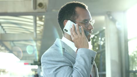 smiling businessman with cell phone at train station