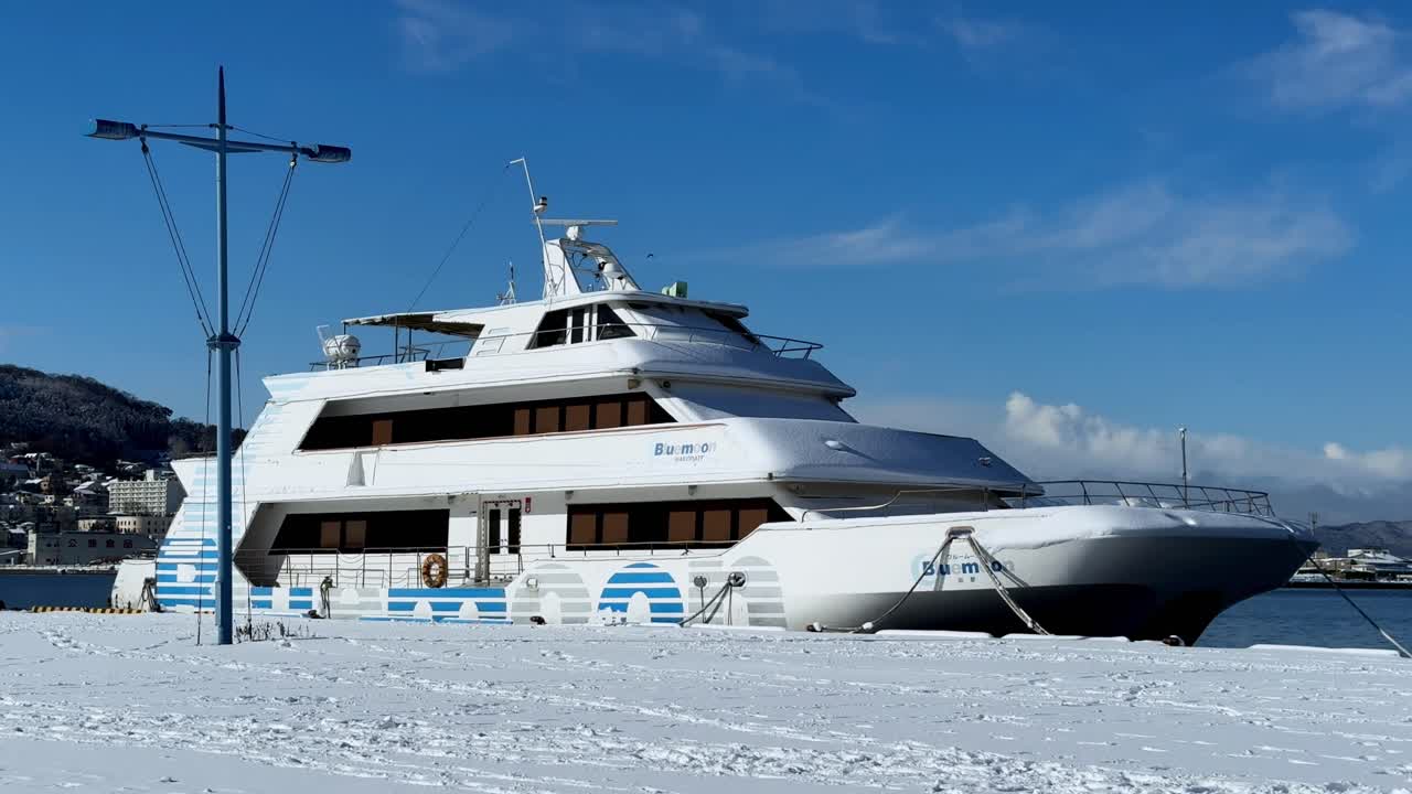 Yacht innevato ormeggiato a Hakodate, in Giappone, sotto un cielo azzurro