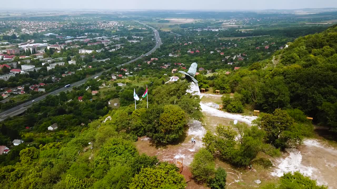 volando sobre la ciudad de tatabánya en hungría, la estatua del pájaro turul y la vista de las banderas húngaras
