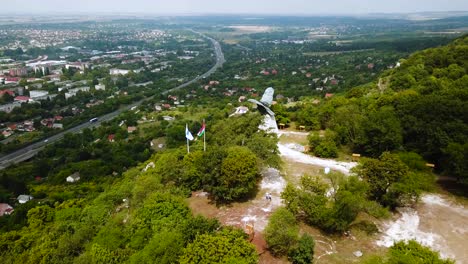 flying over tatabánya city in hungary, turul bird statue and hungarian flags view