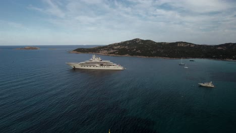 Luftumlauf-über-Einer-Megayacht-Eines-Russischen-Milliardärs-Oligarchen,-Die-In-Einer-Kleinen-Bucht-An-Der-Smaragdgrünen-Küste-Sardiniens-Verankert-Ist