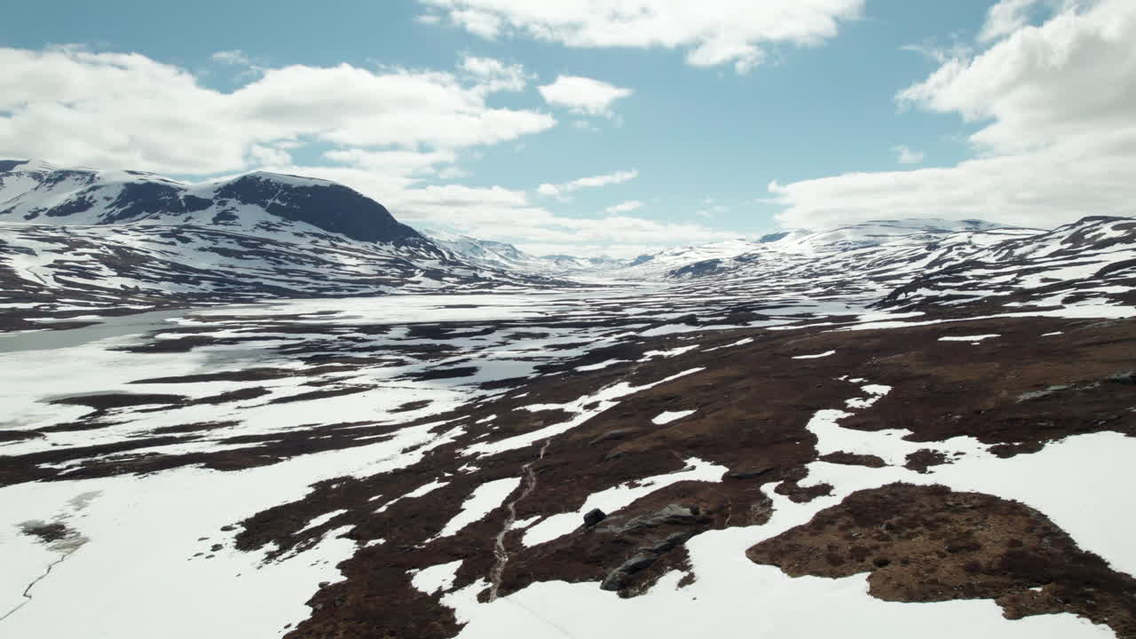 Luftfoto af en lille sti i et fantastisk, fredfyldt svensk bjerg- og sølandskab, sne på Kungsleden i Abisko Nationalpark, drone følger stien