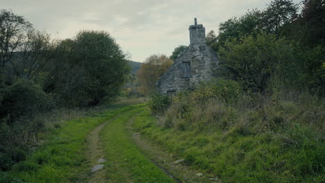 old stone house next to a wooded pathway