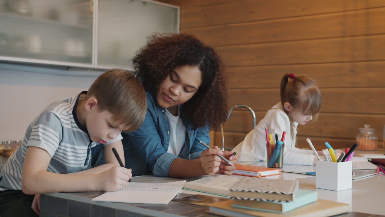 Children doing homework with tutor in the kitchen