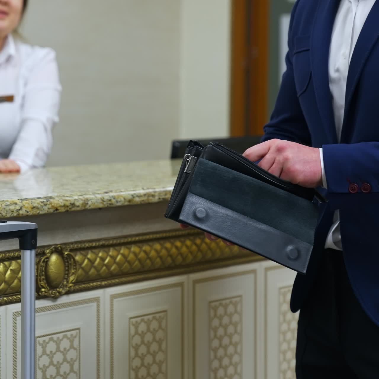 Man at the reception desk in the hotel. Businessman in suit with a purse in hands looking for key card from the room. Business trip