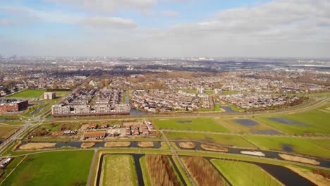 aerial pan right view across barendrecht green fields and town with rotterdam skyline in distance