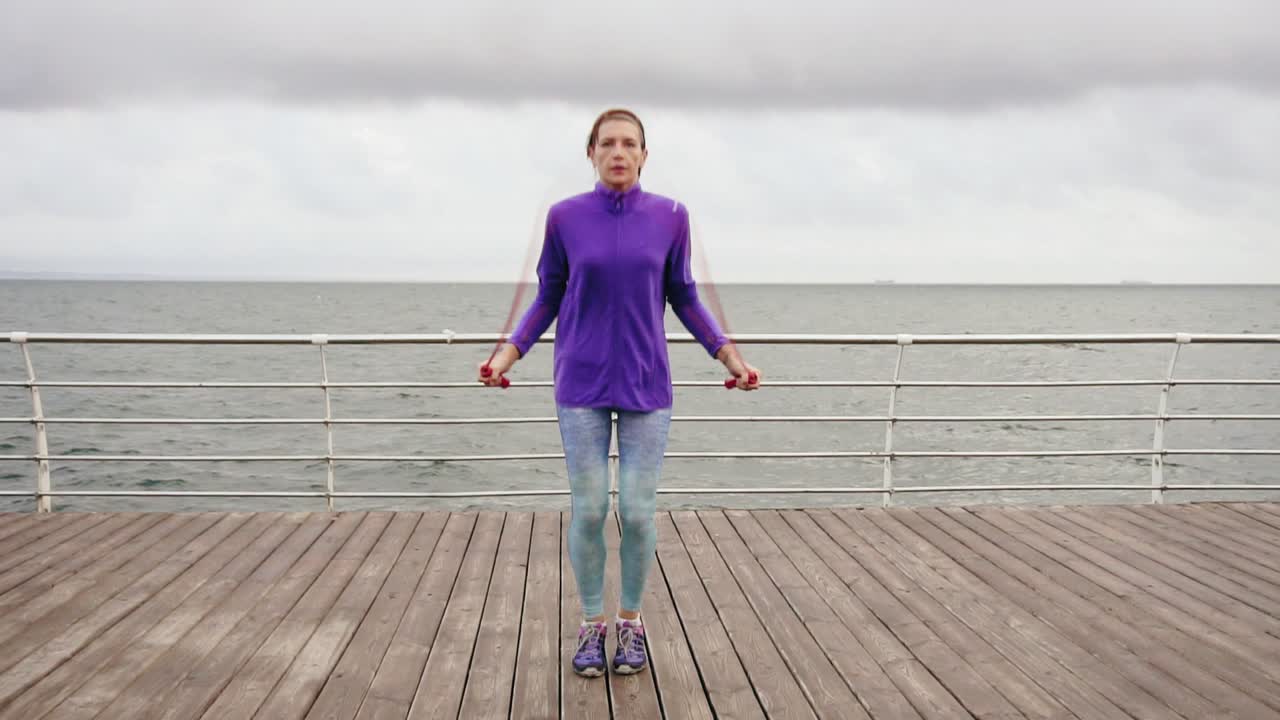 Young woman working out on the jump rope. Outdoor sports. Girl jumping on a skipping rope by the sea. Slow Motion shot
