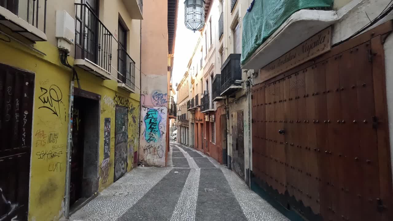 Morning light casts a golden glow over the Albaicin narrow, winding alleys. White Moorish facades bask in tranquil serenity, reflecting the historic charm of this Granada neighborhood. Granada, Spain