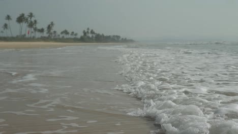 Toma-En-Cámara-Lenta-De-ángulo-Bajo-De-La-Playa-De-Benaulim-En-Goa-Con-Olas-Tranquilas-Y-Palmeras-En-Un-Día-De-Verano