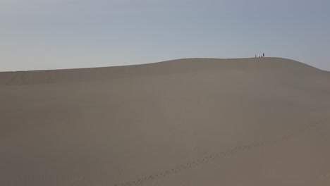 Aerial-Drone-Shot-of-Group-of-People-Walking-on-Sand-Dune-in-Death-Valley