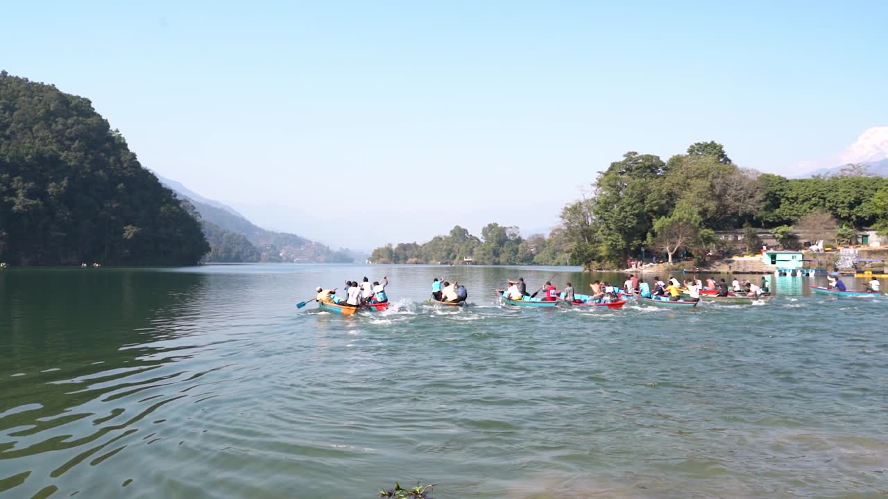 equipo de pueblos compitiendo para ganar la carrera de botes de remo en el lago fewa