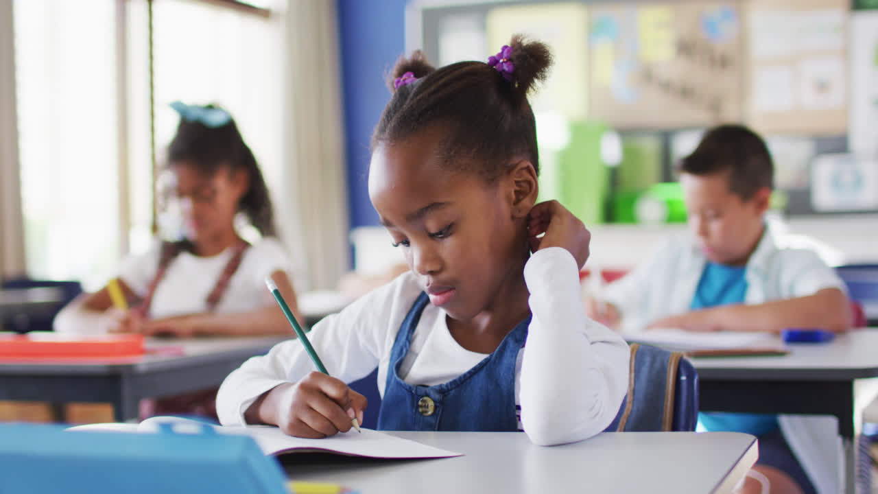 Portrait of african american schoolgirl sitting in classroom, making notes