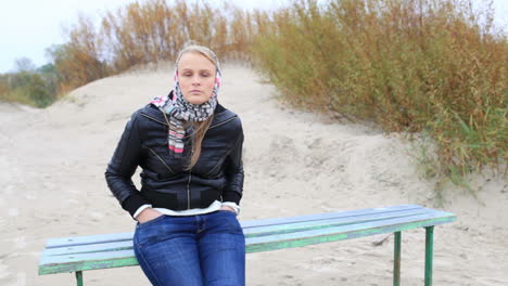 young girl is sitting on a bench near the sea