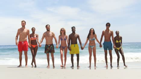 Front-view-of-mixed-race-friends-jumping-together-on-the-beach-4k