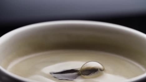 black coffee drop into the filled cup from the coffee machine in slow motion