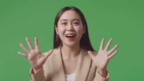 close up of asian business woman showing gesture hands palm saying wow and smiling in the green screen studio