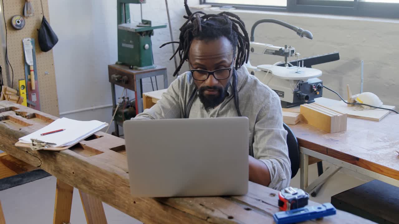 Carpenter using laptop at table 4k