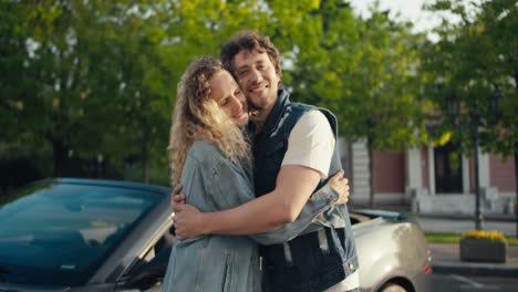una hermosa pareja joven de un chico moreno y una chica rubia están de pie mirando a la cámara y abrazándose contra el