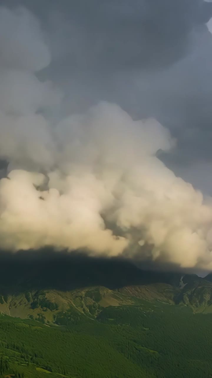 Vertical video: Sunlight penetrating storm cloud above ridge brightening lobes and forming fog