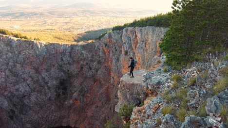 a person going on the edge of red lake the biggest sinkhole in europe