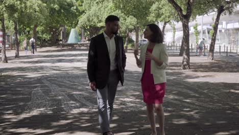 two people wearing formal wear talking during stroll in park.