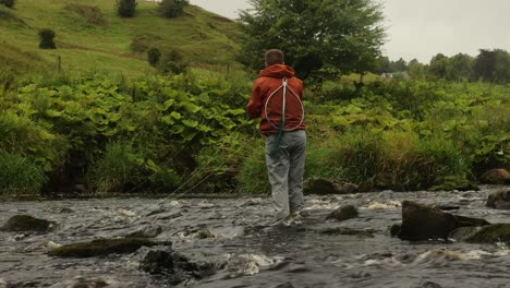 hand-held shot of a fly fisherman casting his flies into a small river