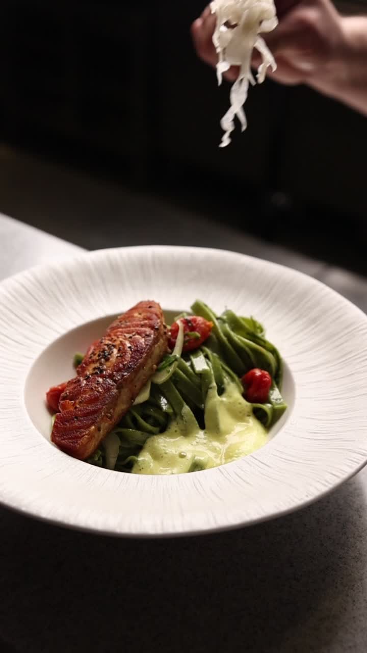 Chef Garnishing a Gourmet Salmon and Green Pasta Dish