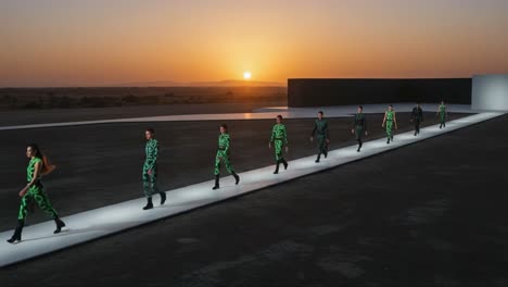 a stunning fashion showcase at sunset: models strut down a sleek runway dressed in eye-catching neon designs against a breathtaking natural backdrop