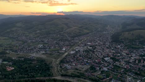 Un-Dron-Captura-Una-Impresionante-Puesta-De-Sol-Sobre-El-Paisaje-Urbano-Y-Las-Colinas-De-Gura-Humorului